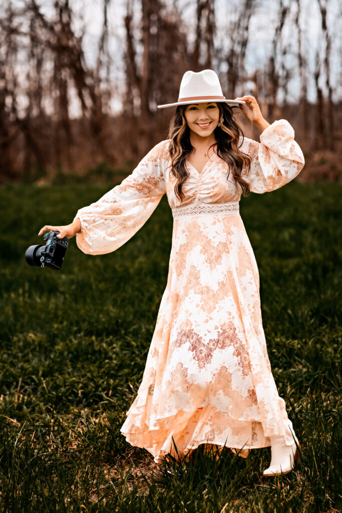 Emily Belanger holding a camera and her hat.