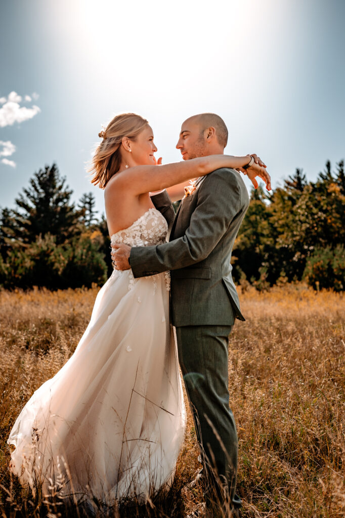 bride and groom look at eachother in a field with golden morning light