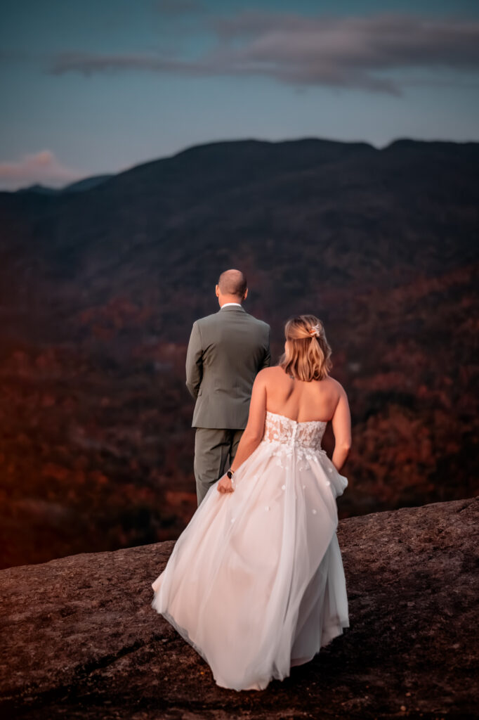 groom looks out at the mountains in the fall during first look with bride.
