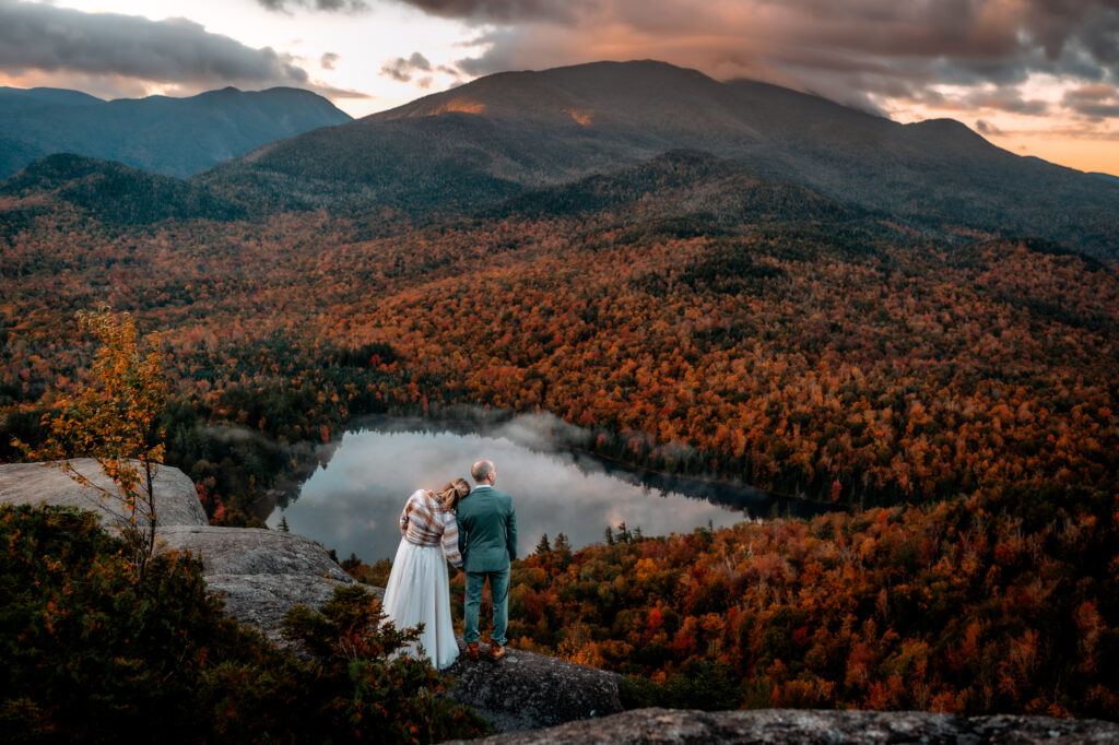 A couple who just eloped on top of Mount Jo in the fall looks out at Heart Lake in the Adirondacks. 