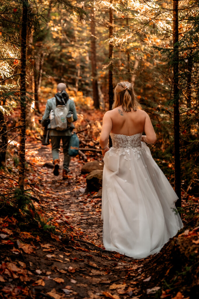 bride and groom hike through fall foliage forest