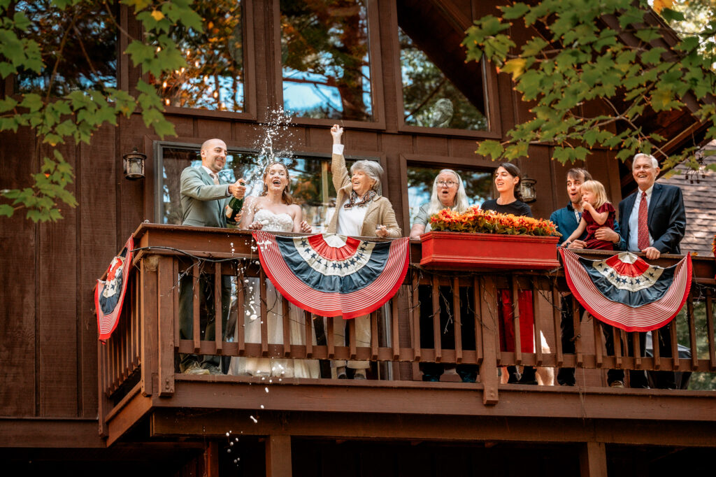 A family pops champagne on a balcony at an air bnb cabin in wilmington ny after a couple eloped. 