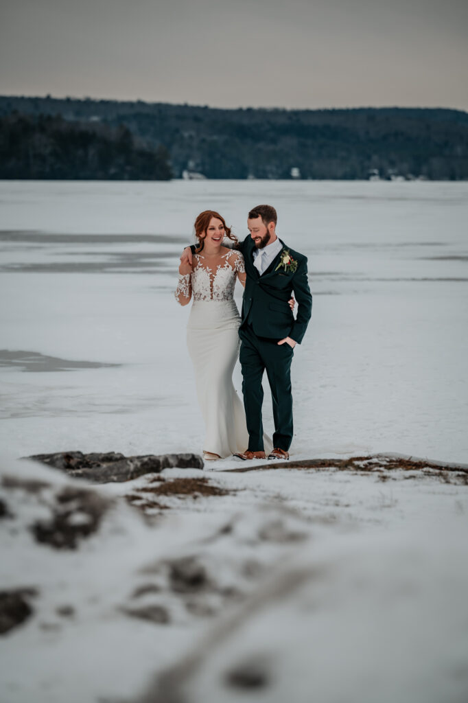 a couple walks on a frozen lake after getting married in the winter. 