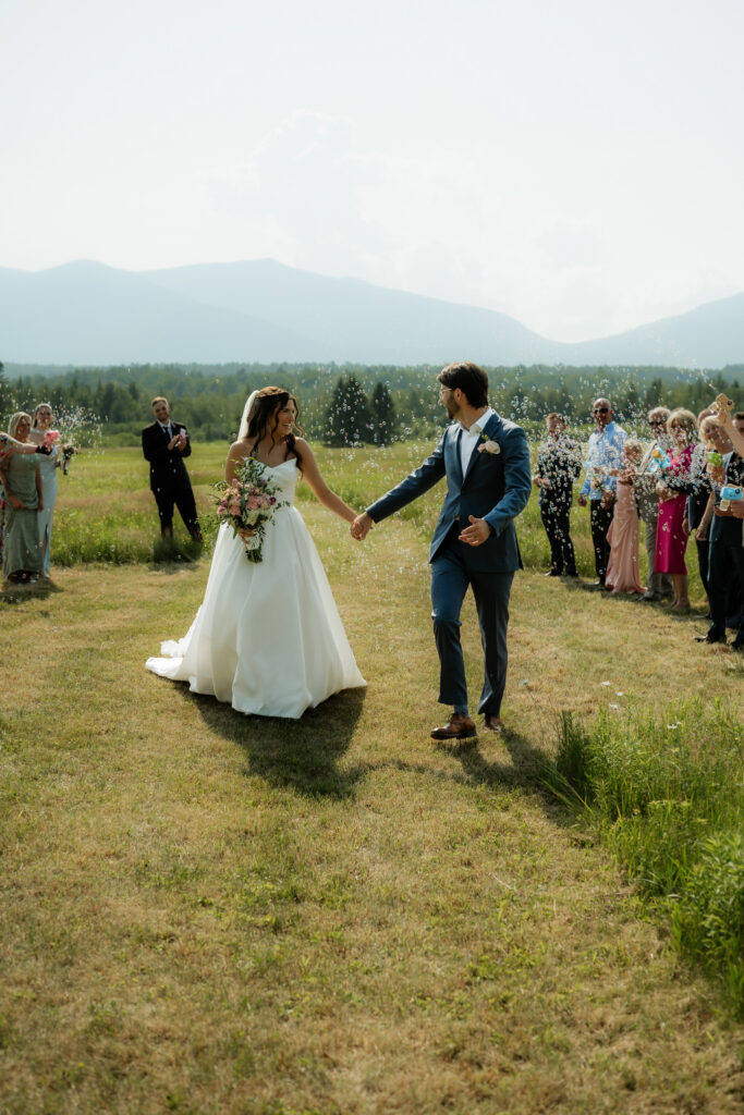 An intimate wedding in the Adirondacks with the couple walking down the isle and bubbles behind them. 