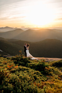 A couple dances on a high peak summit in the adirondack mountains after eloping at sunset.