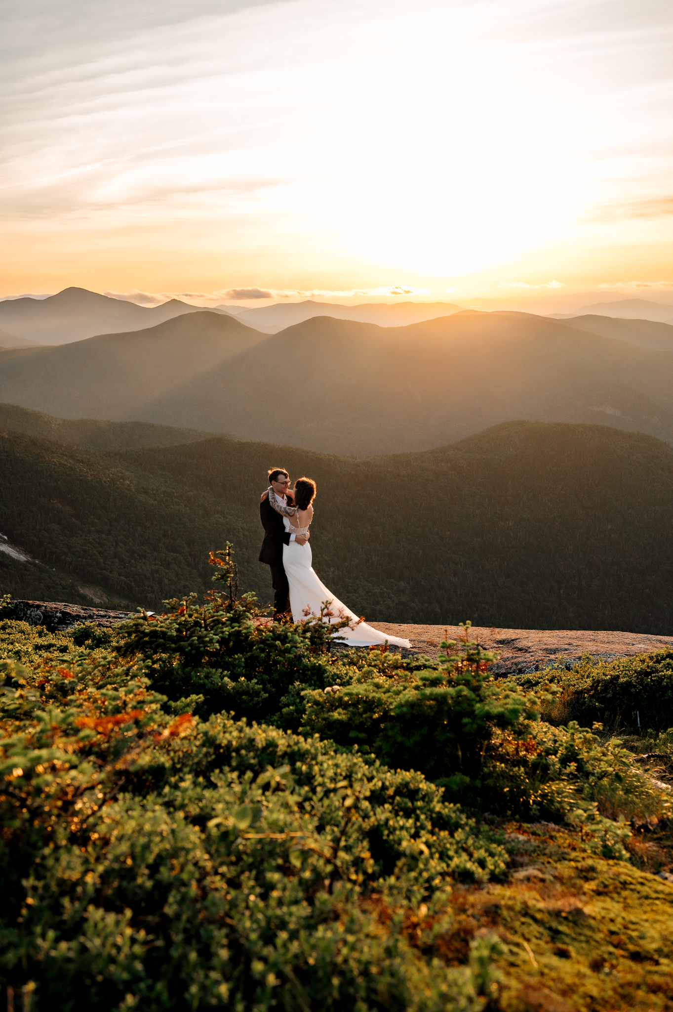 A couple dances on a high peak summit in the adirondack mountains after eloping at sunset.