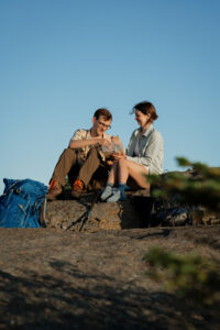 A couple eats ramen noodles at the top of a mountain in the Adirondacks.