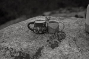 A picture of two handmade mugs on a rock.