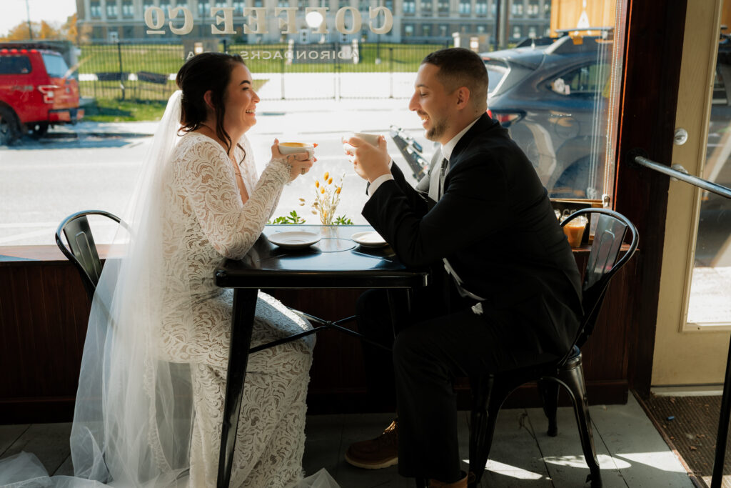 Couple eats brunch at a coffee shop in downtown lake placid in wedding attire.