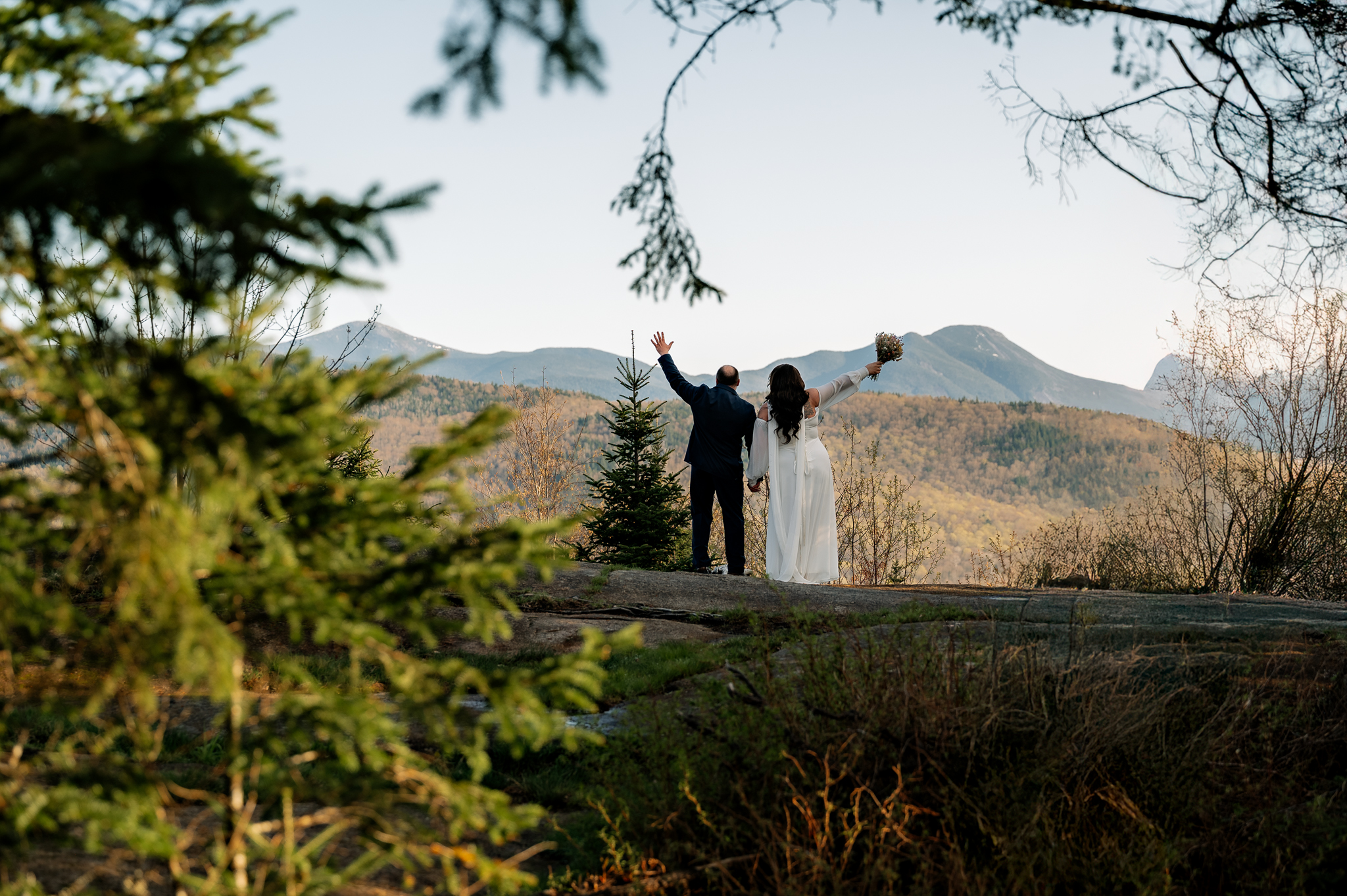 A couple throws up hands looking out at the mountains from Scotts Cobble Weddings.