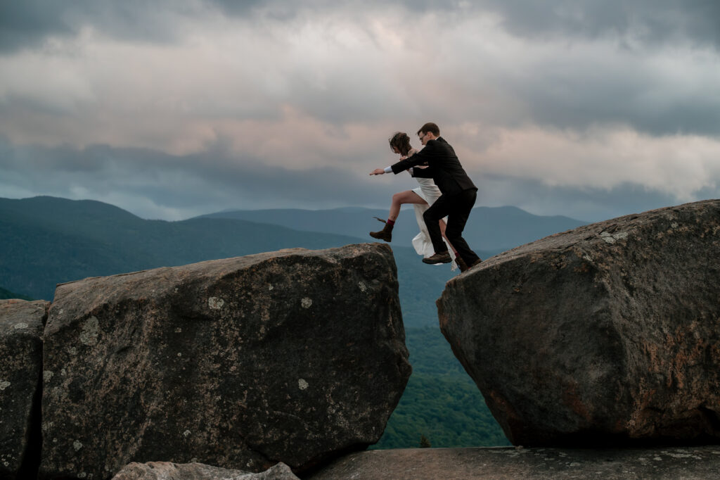 A couple who just eloped jumping boulders in the adirondack mountains