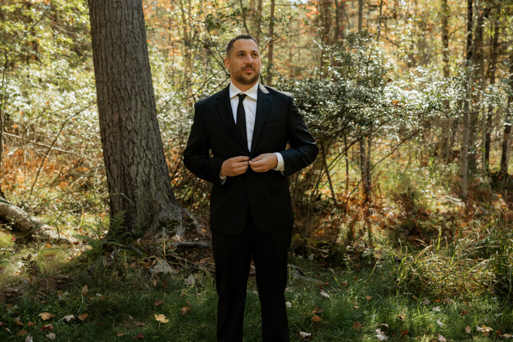 Groom buttons his wedding suit jacket.