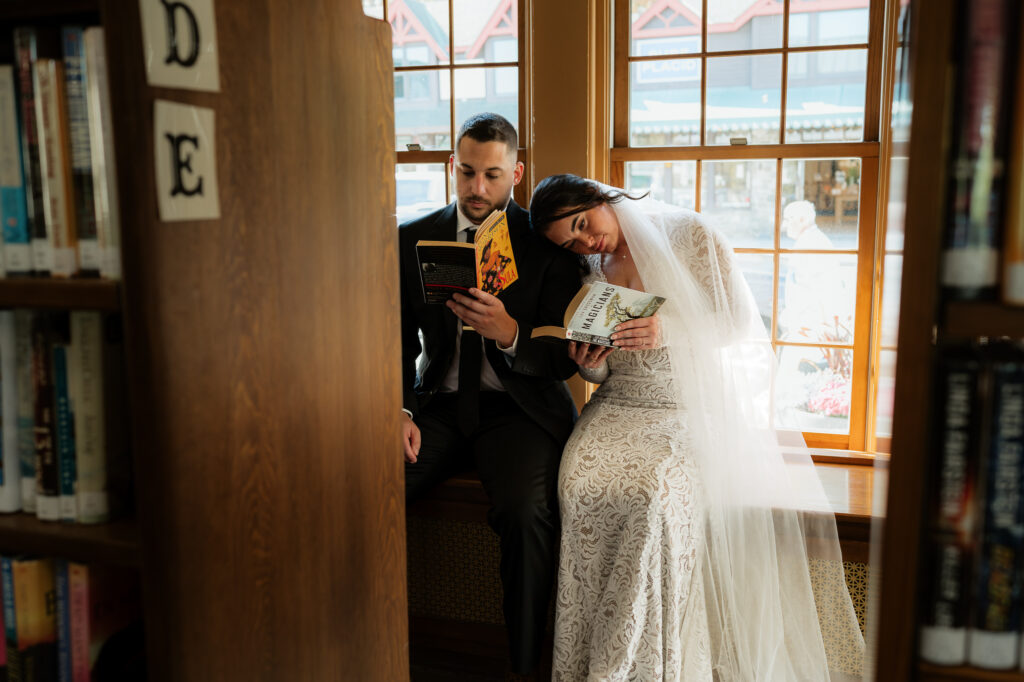 A couple is cuddled up in a library reading books together on their wedding day.