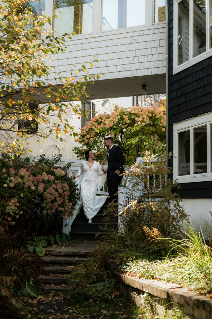 A couple who just got married walks through a library garden in lake placid.