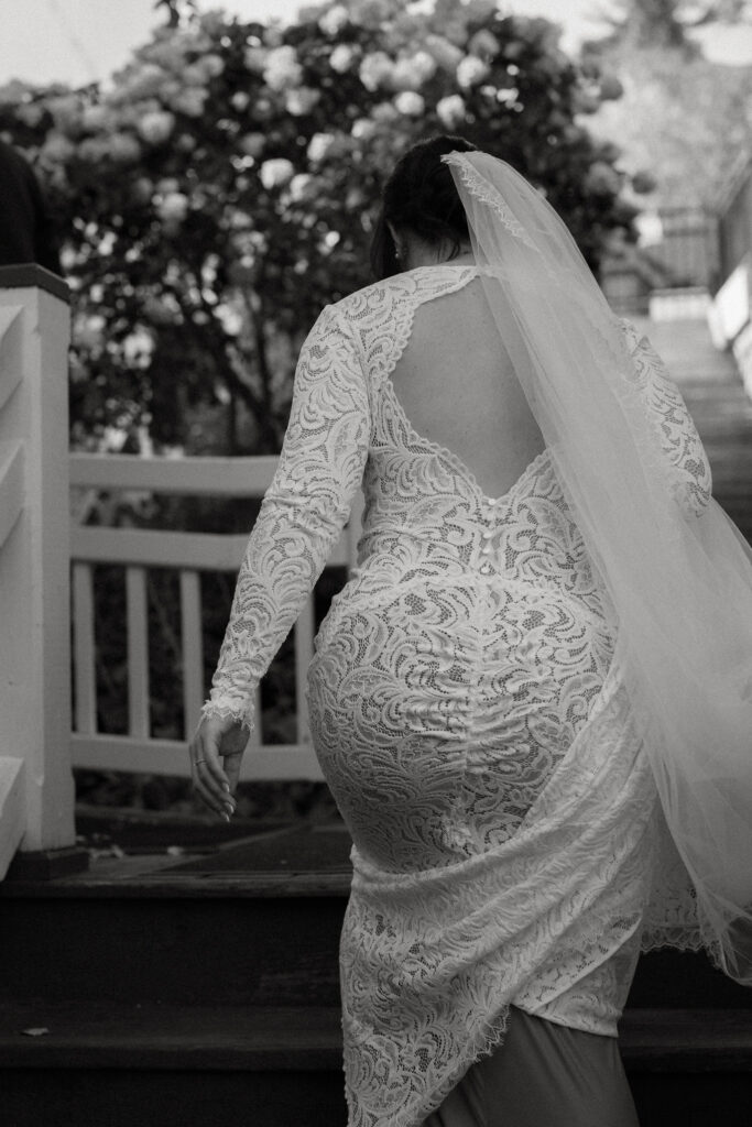 A black and white photo of a bride walking up a set of stairs.