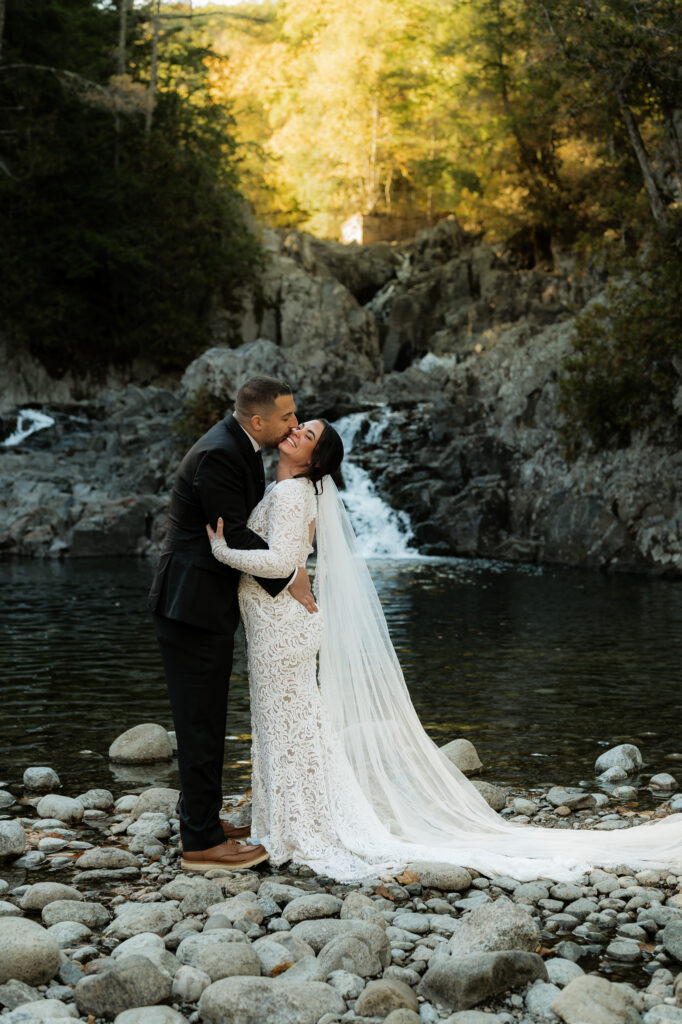 A couple is laughing and having fun at the base of a waterfall in the Adirondacks.