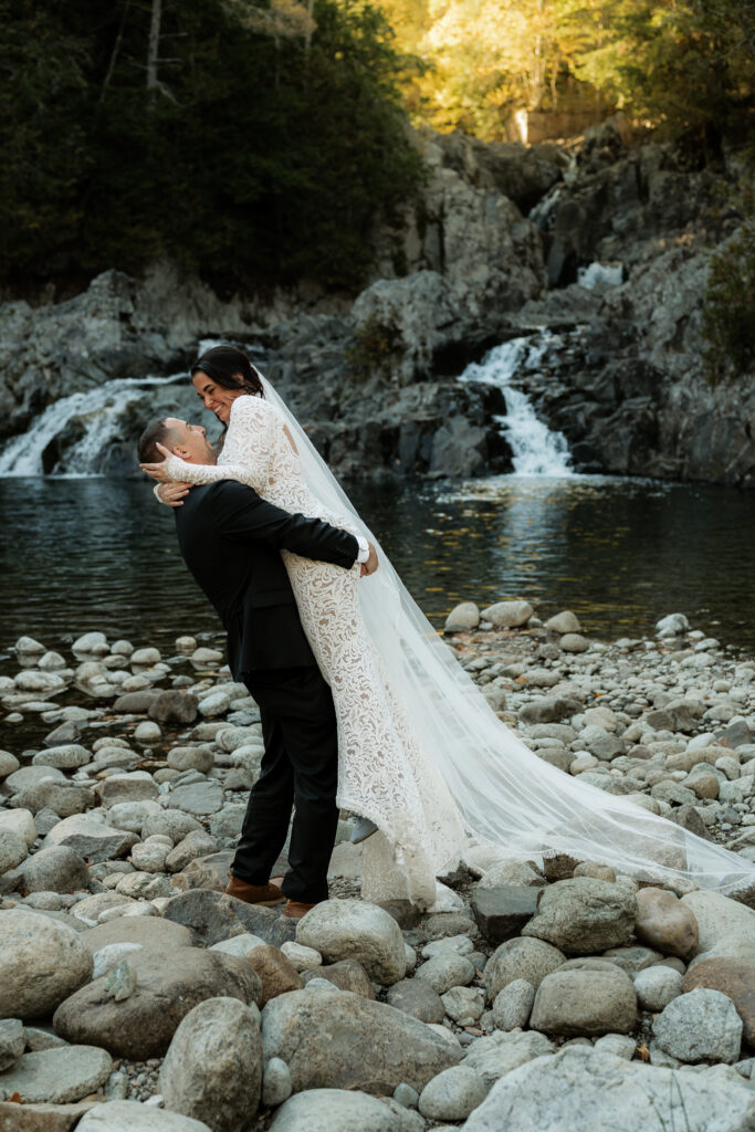 A couple is laughing and having fun at the base of a waterfall in the Adirondacks.