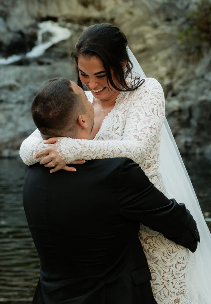 A couple is laughing and having fun at the base of a waterfall in the Adirondacks.