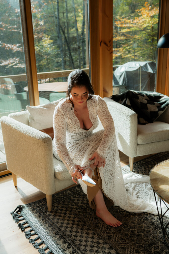 An elopement bride putting her wedding shoes on while on a couch.