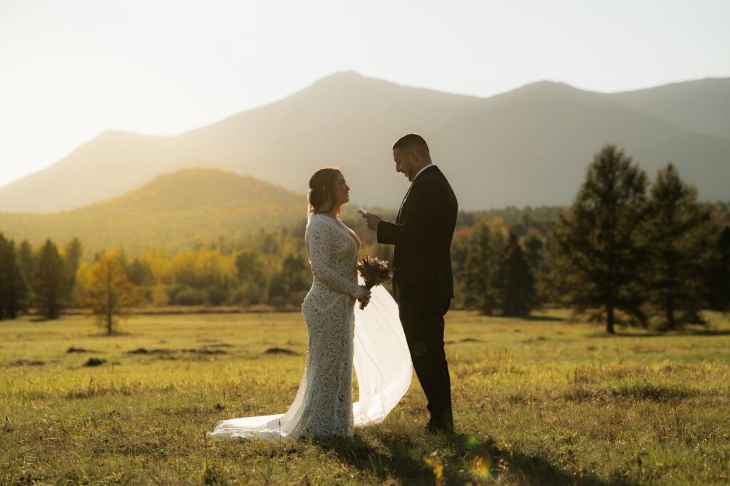 A wilmington ny elopement where a couple is standing in a field exchanging vows at sunset.