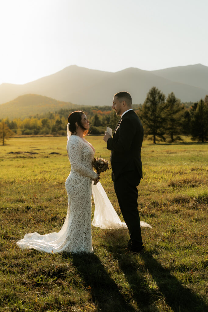 A wilmington ny elopement where a couple is standing in a field exchanging vows at sunset.