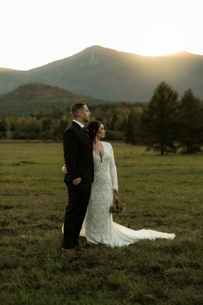 A couple watches the final light leave the valley in the adirondacks as the sun sets over the mountains.