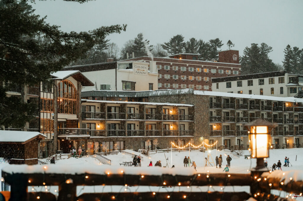 Golden Arrow Resort in Lake Placid on a Winter evening with lights and people playing in the snow.