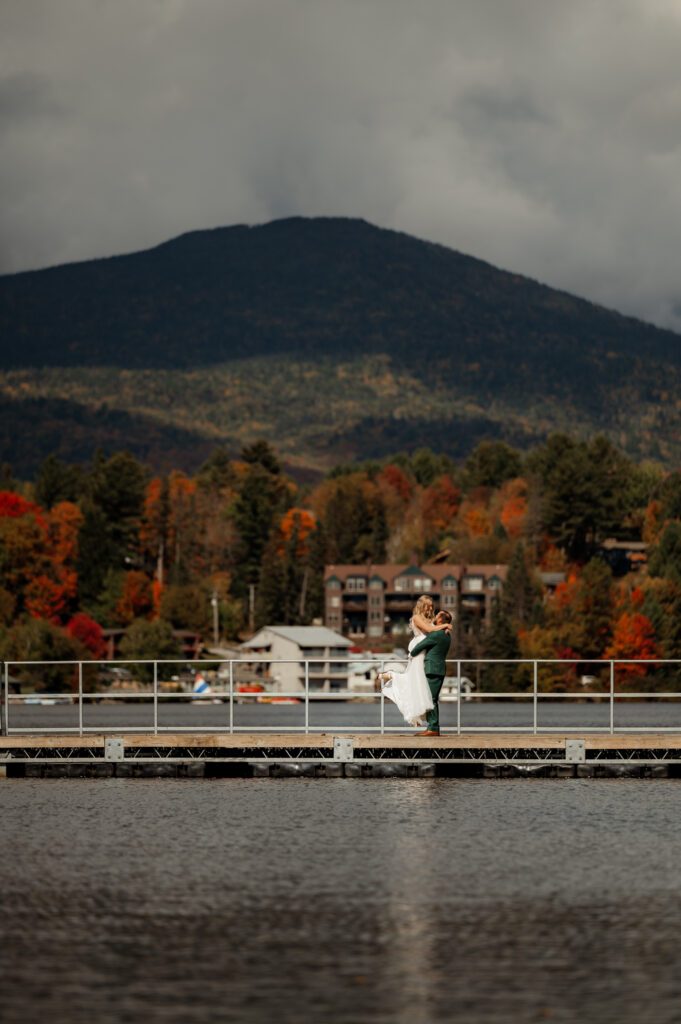 A couple embraces on a dock along Mirror Lake in downtown Lake Placid New York before getting married.