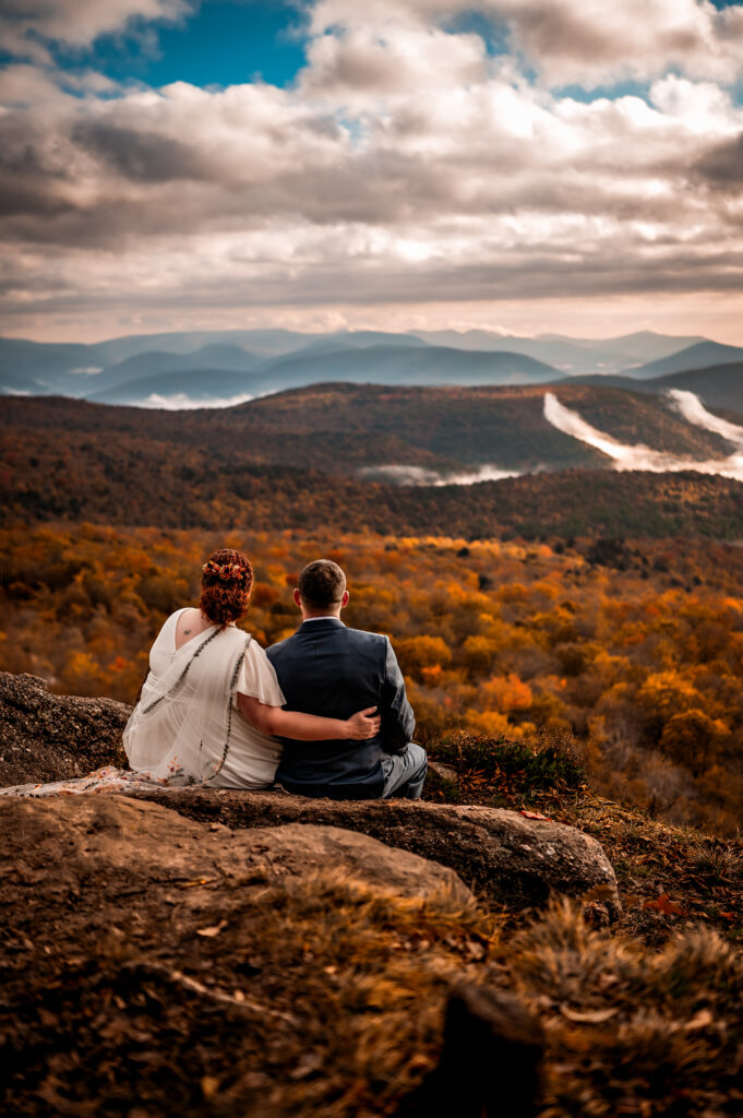 A fall sunrise elopement with a couple on top of a mountain overlooking the foliage.
