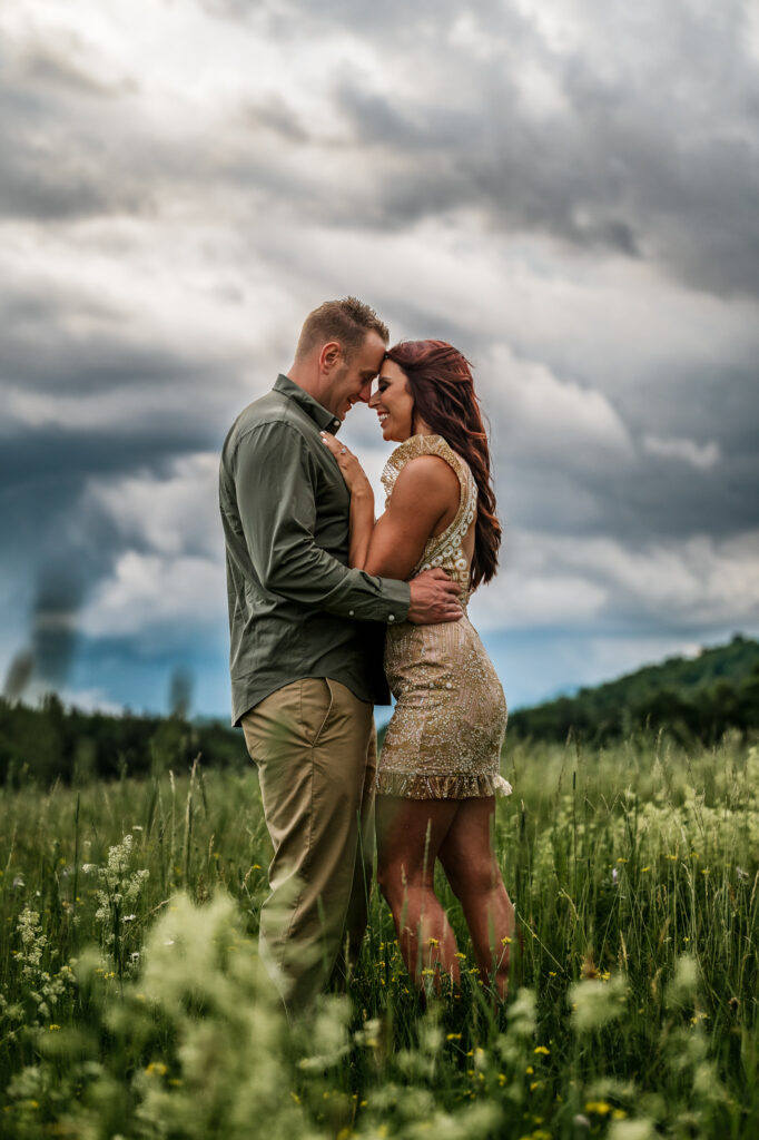A couple touching forheads among the clouds in a flower field on a spring day.