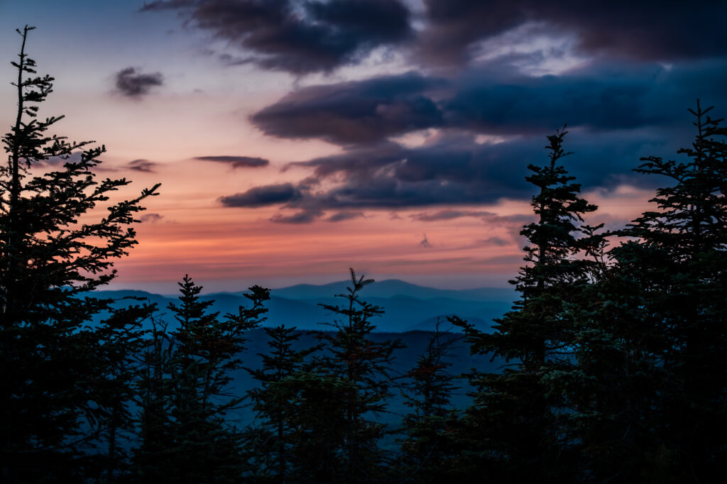 Sunset on Hurricane mountain with a silhouette of trees.