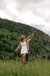 A couple dances in a field of flowers on a hike in the adirondack mountains.