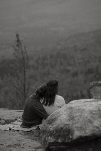 A couple holds eachother on a rock face.