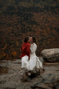 Two brides kissing in the rain.